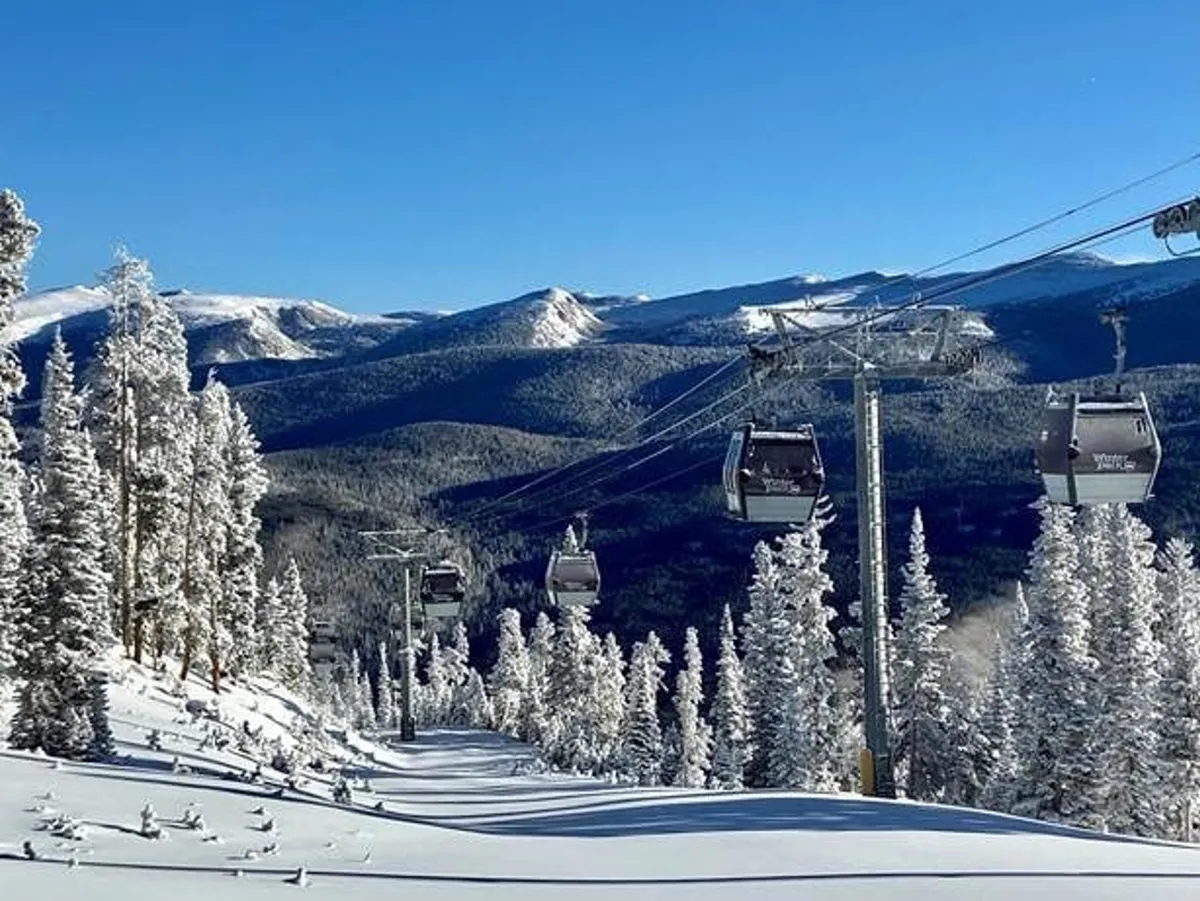 Snow-covered slopes with ski lift gondolas gliding above, framed by distant mountains and tall pine trees. The scene is serene yet adventurous, capturing the essence of winter activities available nearby.