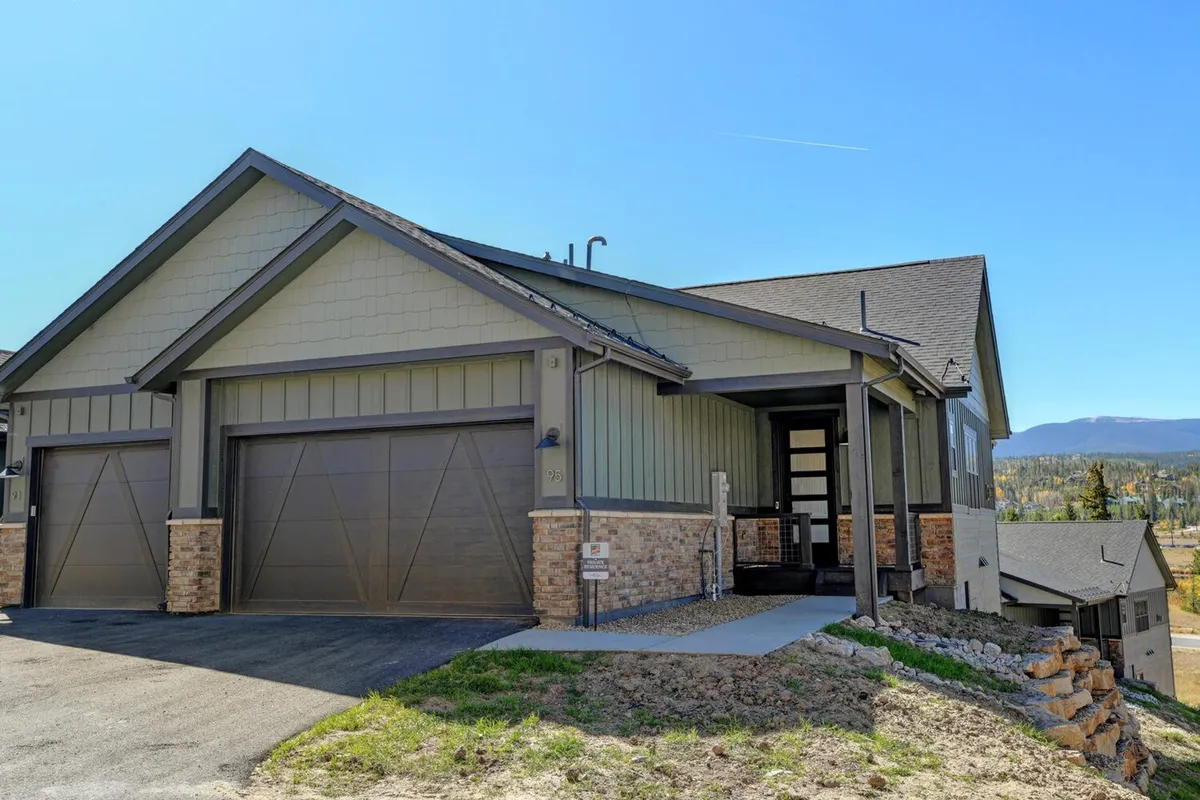 A view of the property’s modern exterior with stone accents, large garage doors, and attractive landscaping. The inviting porch and surrounding yard offer outdoor space ideal for families and pets to unwind after a day of adventure.